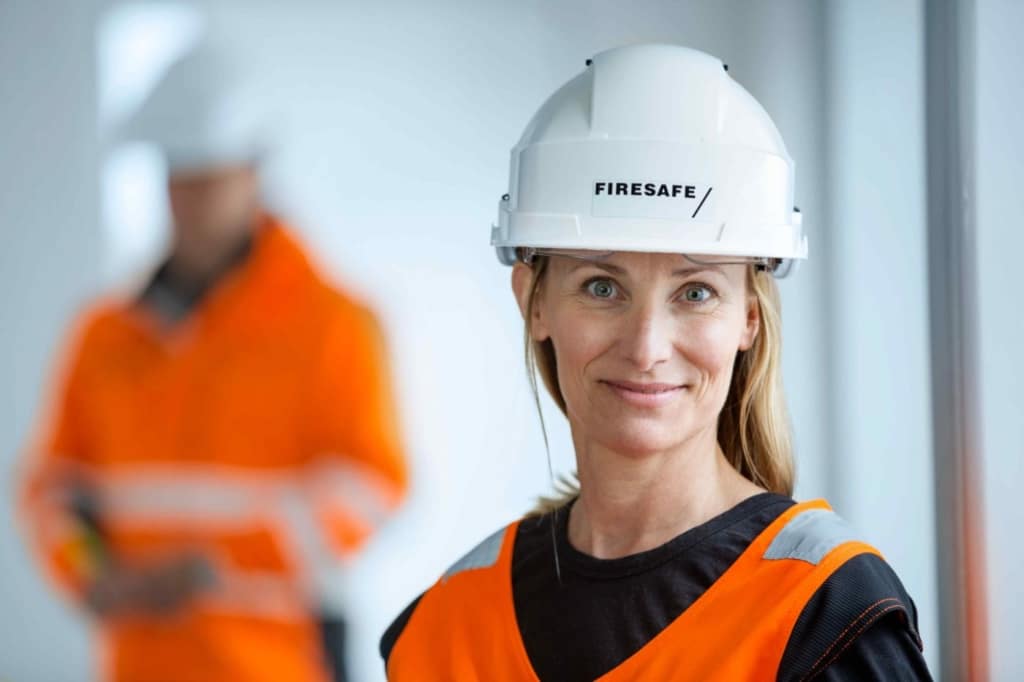 Anne med hjelm og synlighetsvest på byggeplass